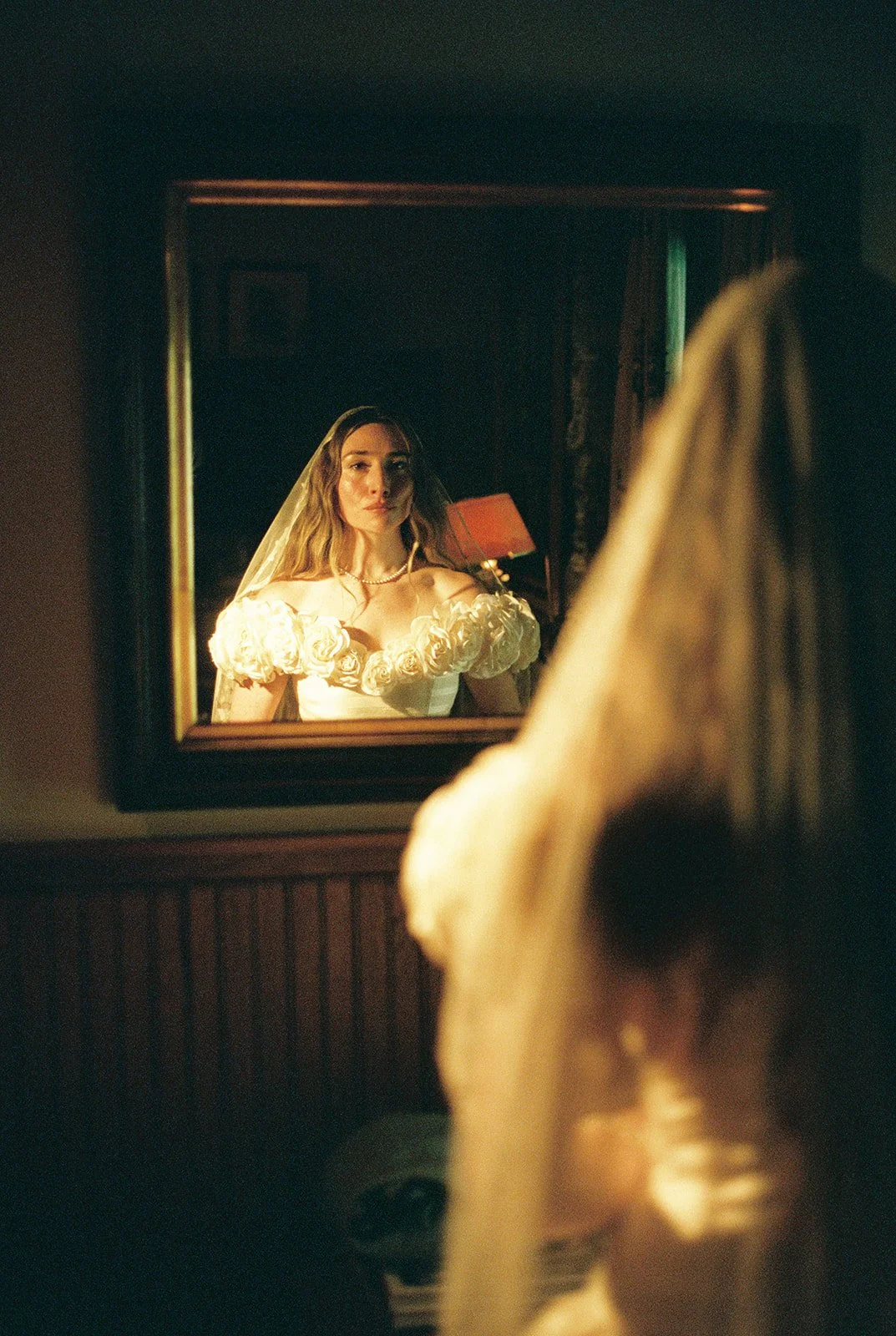 Indoor bridal portrait on film of the bride looking at herself in the mirror before her ceremony.