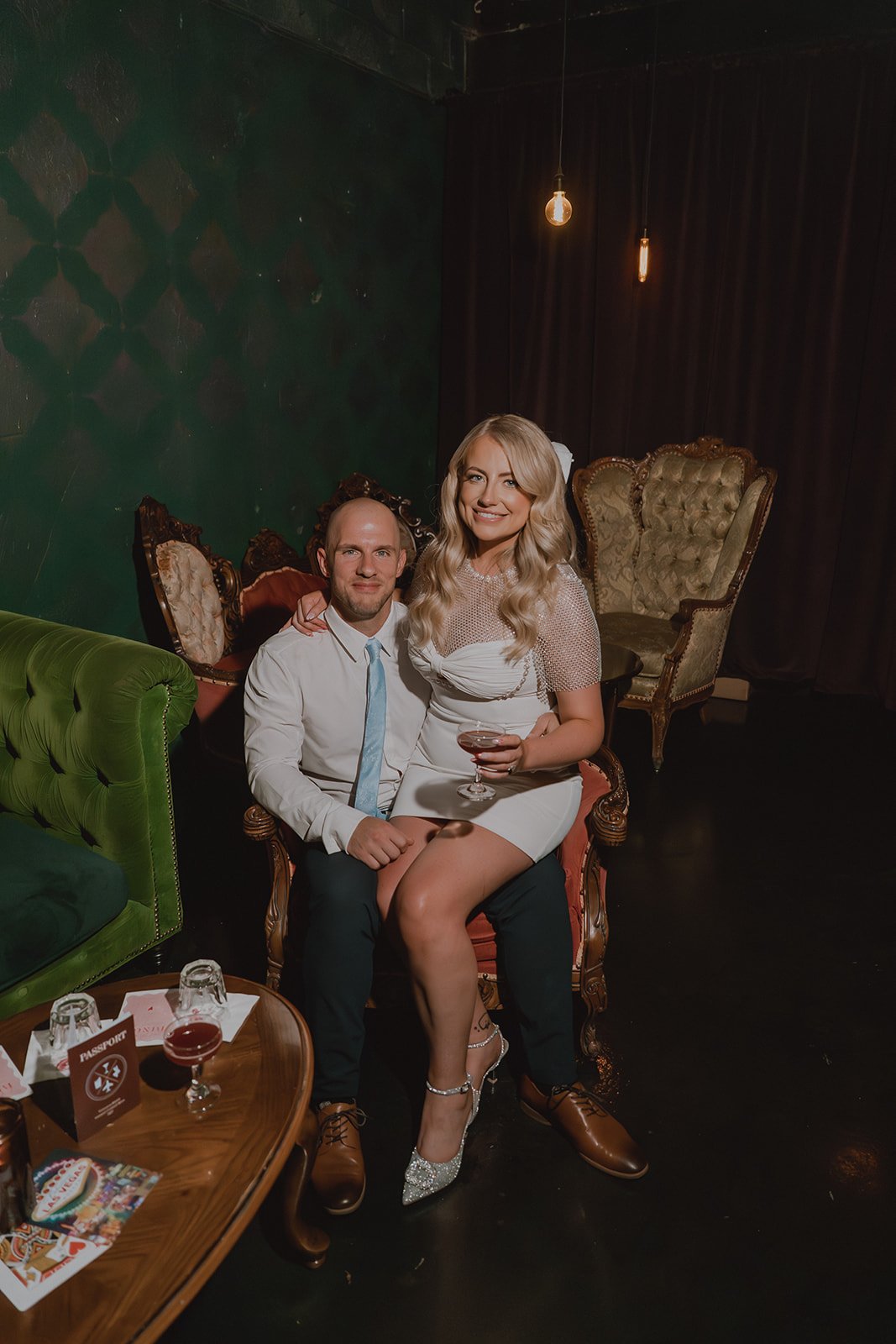 Bride and groom holding cocktails while seated together at Velveteen Rabbit during their Las Vegas micro wedding reception.