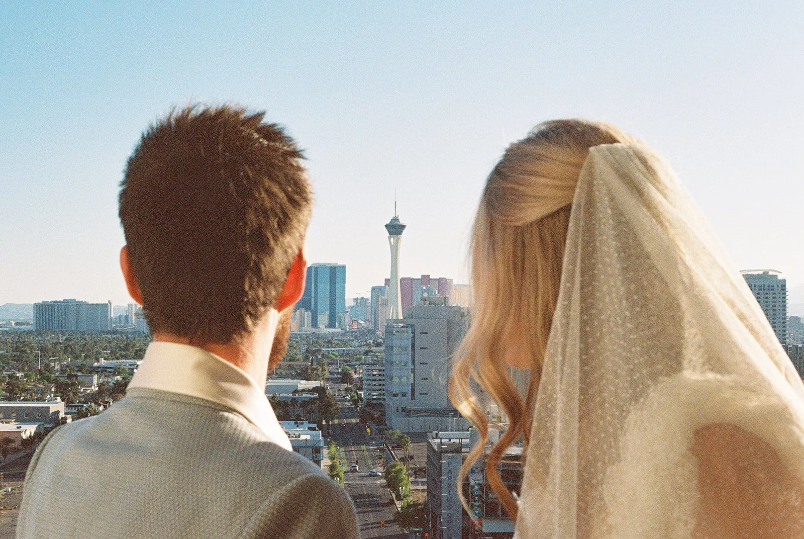 Wide shot of the couple enjoying views of Las Vegas from the balcony at Jackie Gaughan Suite at El Cortez in Las Vegas on film.