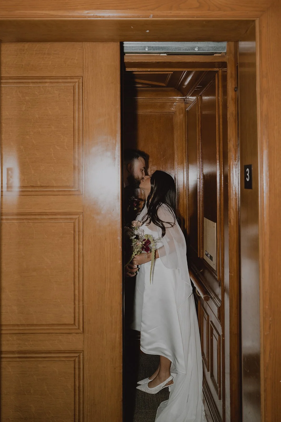 Couple kissing in a vintage elevator at Old Orange County Courthouse.