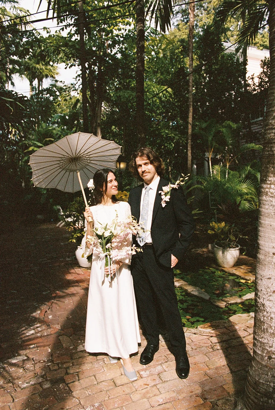 Bride and groom walking the pathways at Old Town Manor in Key West, Florida for their elopement photos on 35mm film.