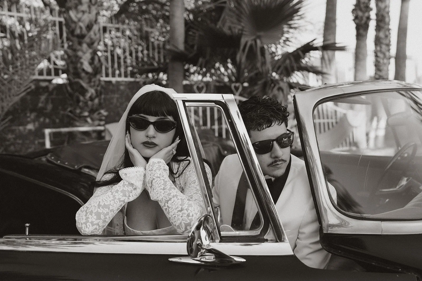 Black and white photo of a bride and groom posing inside a classic car for their Las Vegas elopement photos.