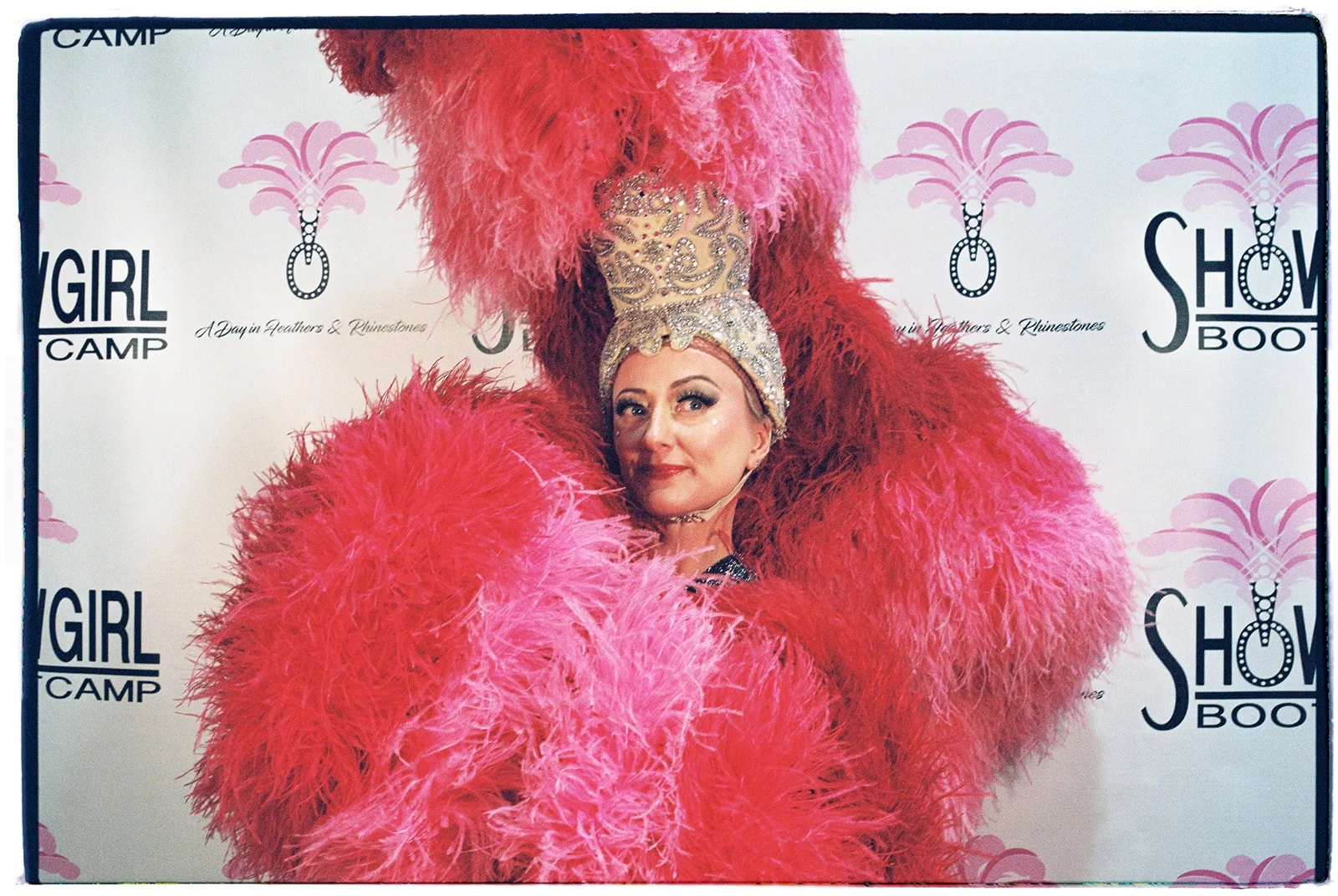 Zoey Goto posing in a feathered showgirl costume during the Showgirl Bootcamp Experience in Las Vegas, photographed on film.
