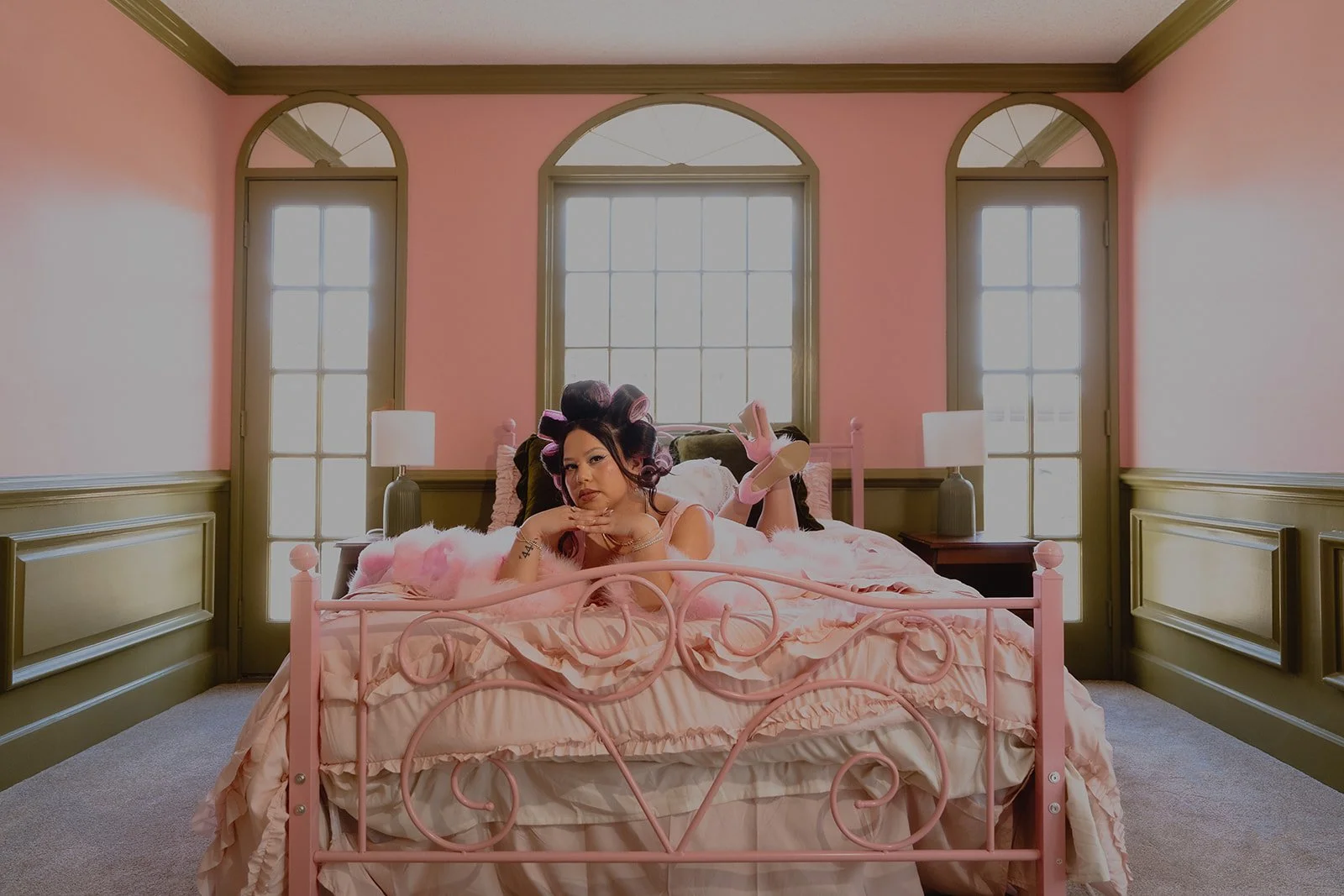 Woman posing on a bed inside The Pink Portal Den in Las Vegas.