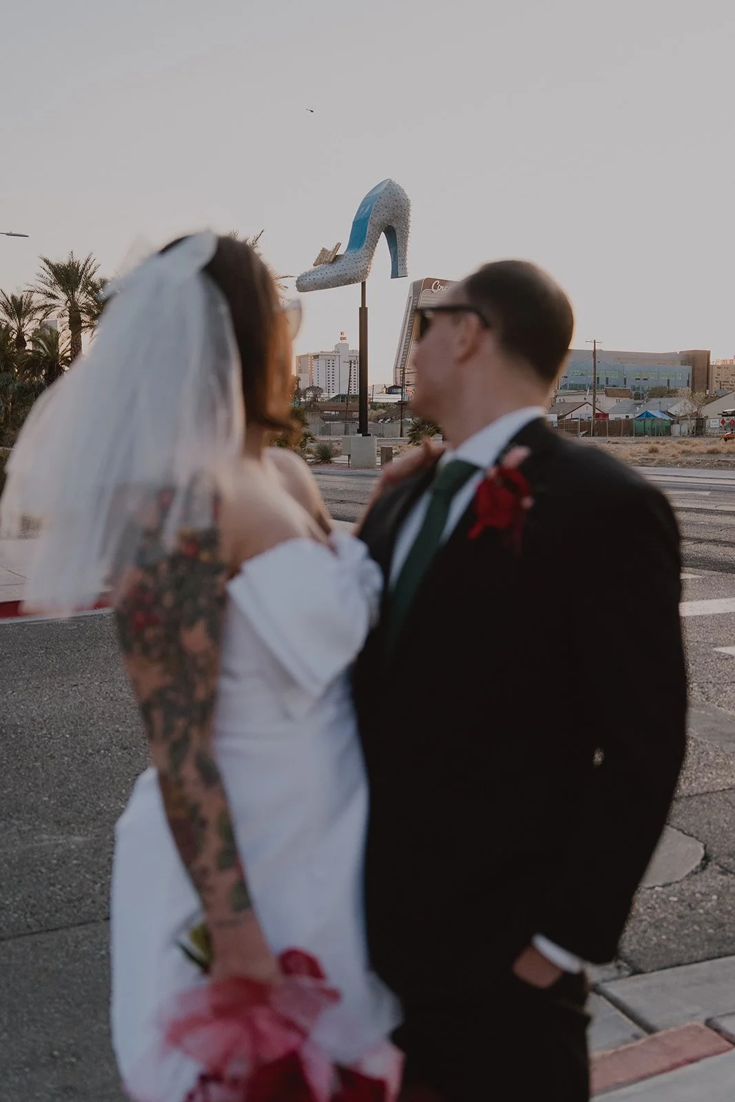 Bride and groom admiring a large heel statue in Las Vegas.