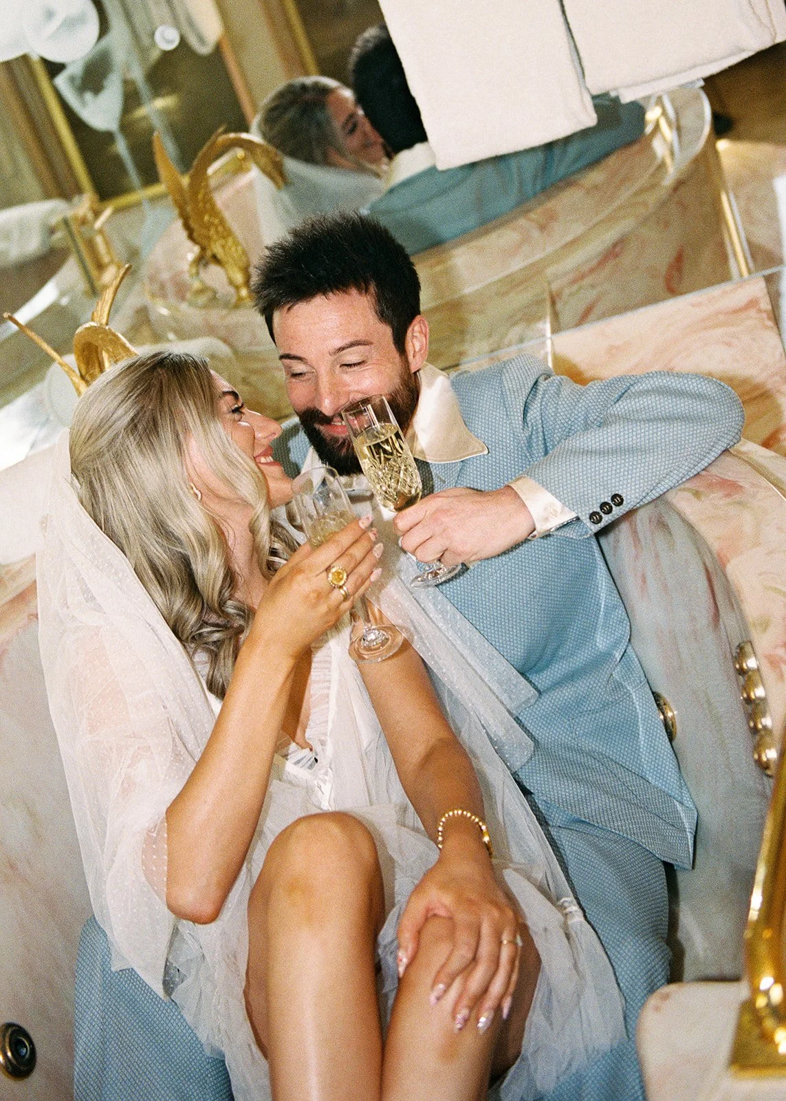Couple having champagne during their elopement inside the Jackie Gaughan Suite at El Cortez Hotel in Las Vegas on film.