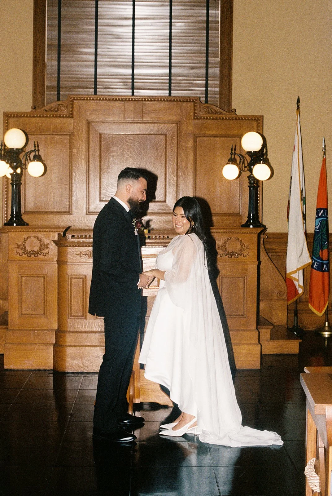 35mm film photo of a couple holding hands at the alter for their Old Orange County Courthouse wedding.