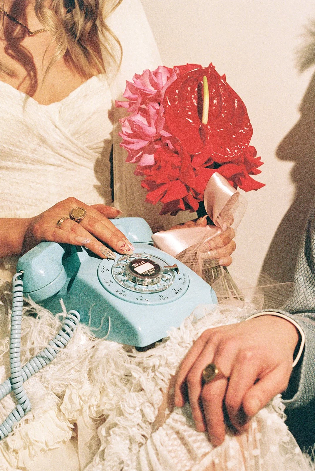 Close up shot of a bride and groom posing with a blue vintage rotary phone.