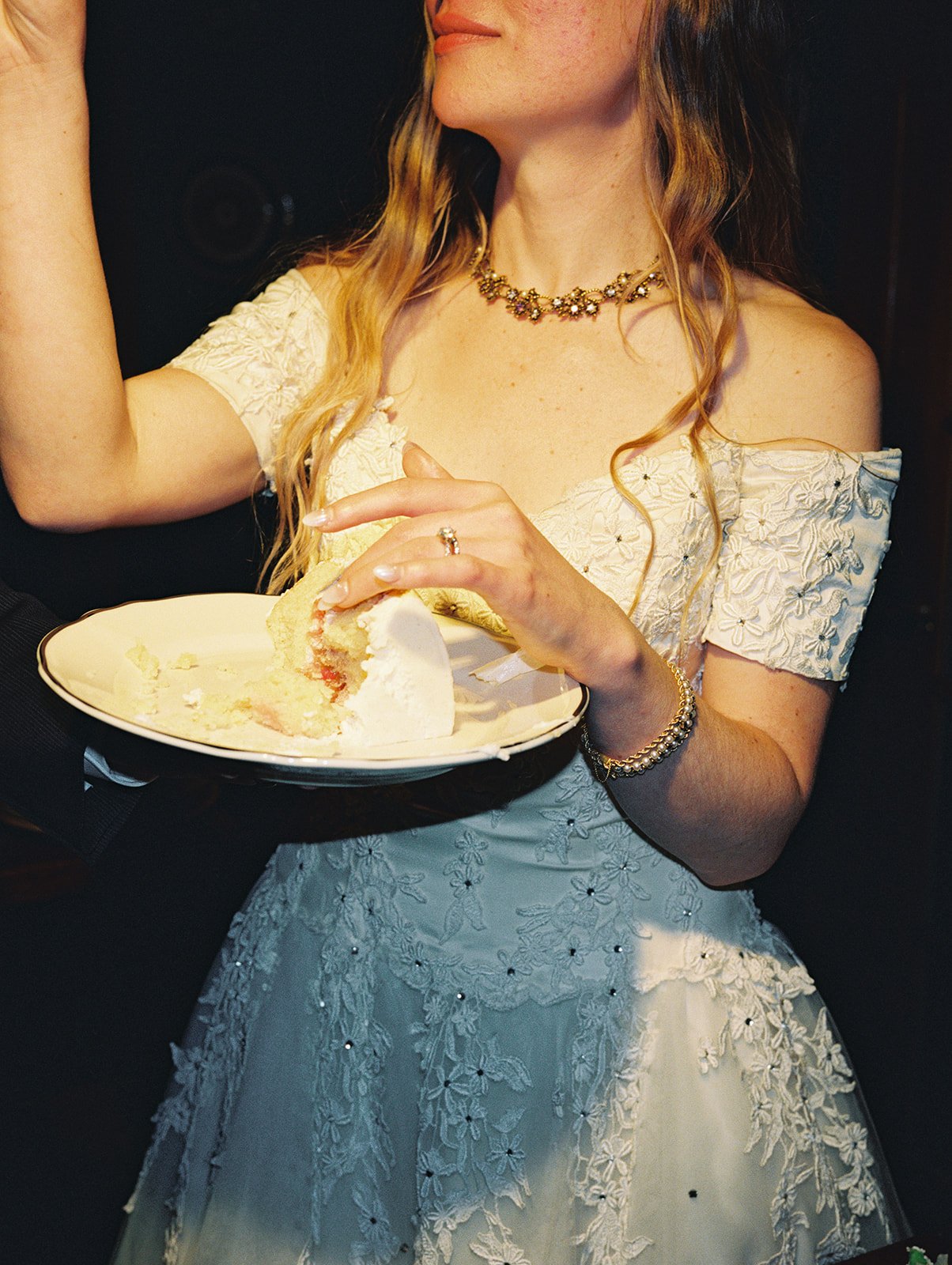Close up photo of a bride with a slice of cake during ckae cutting on film.