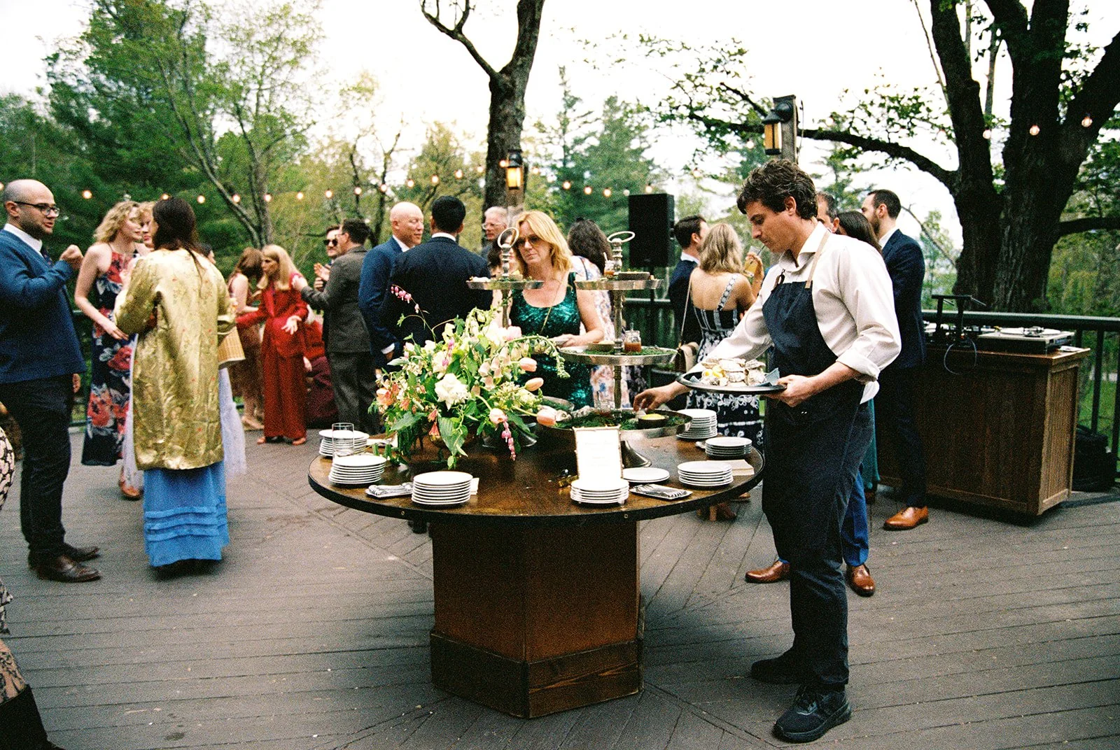 Film photo of guests enjoying cocktail hour around a floral food display on the Deer Mountain Inn terrace.