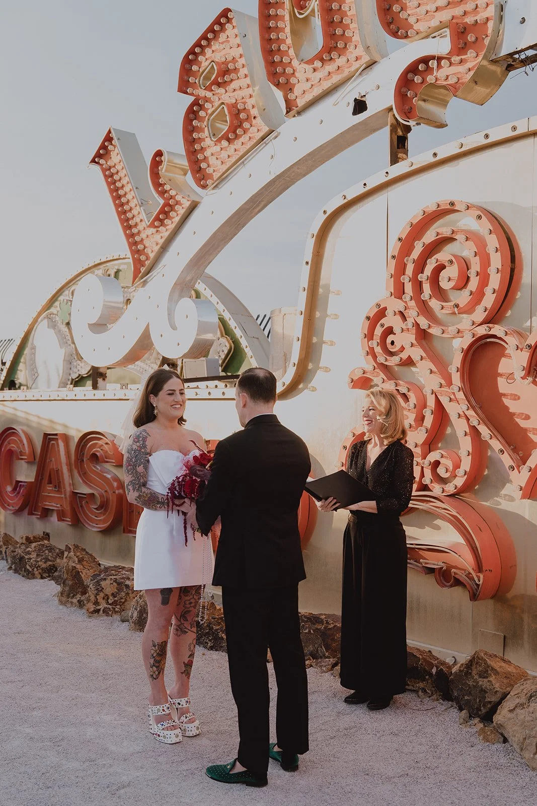 Officiant leading a ceremony in front of vintage neon signs during a Neon Museum Las Vegas wedding.