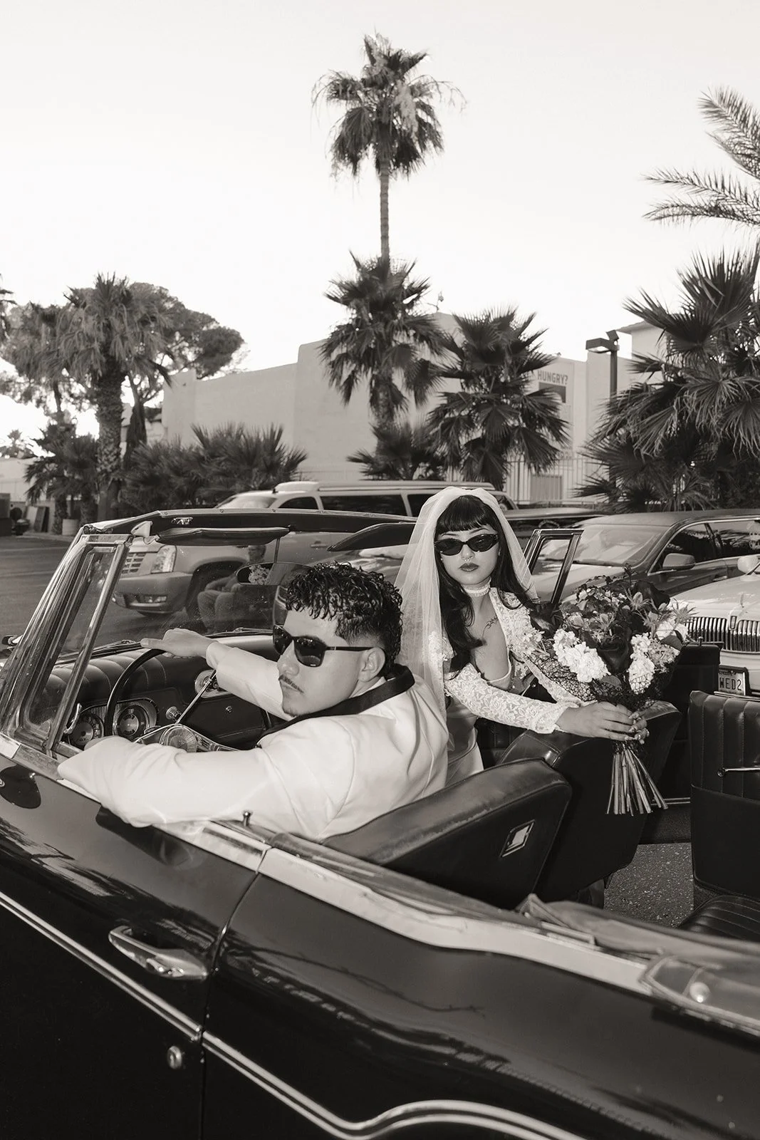 Black and white photo of a bride and groom posing inside a classic car for their Las Vegas elopement photos.