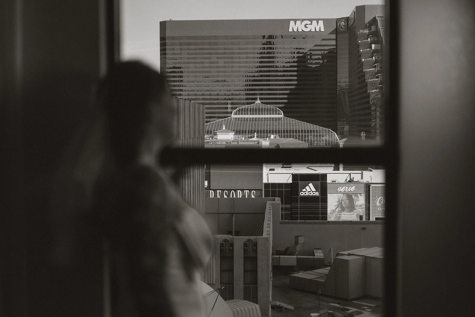 Black and white photo of a bride looking out her hotel window in Las Vegas.