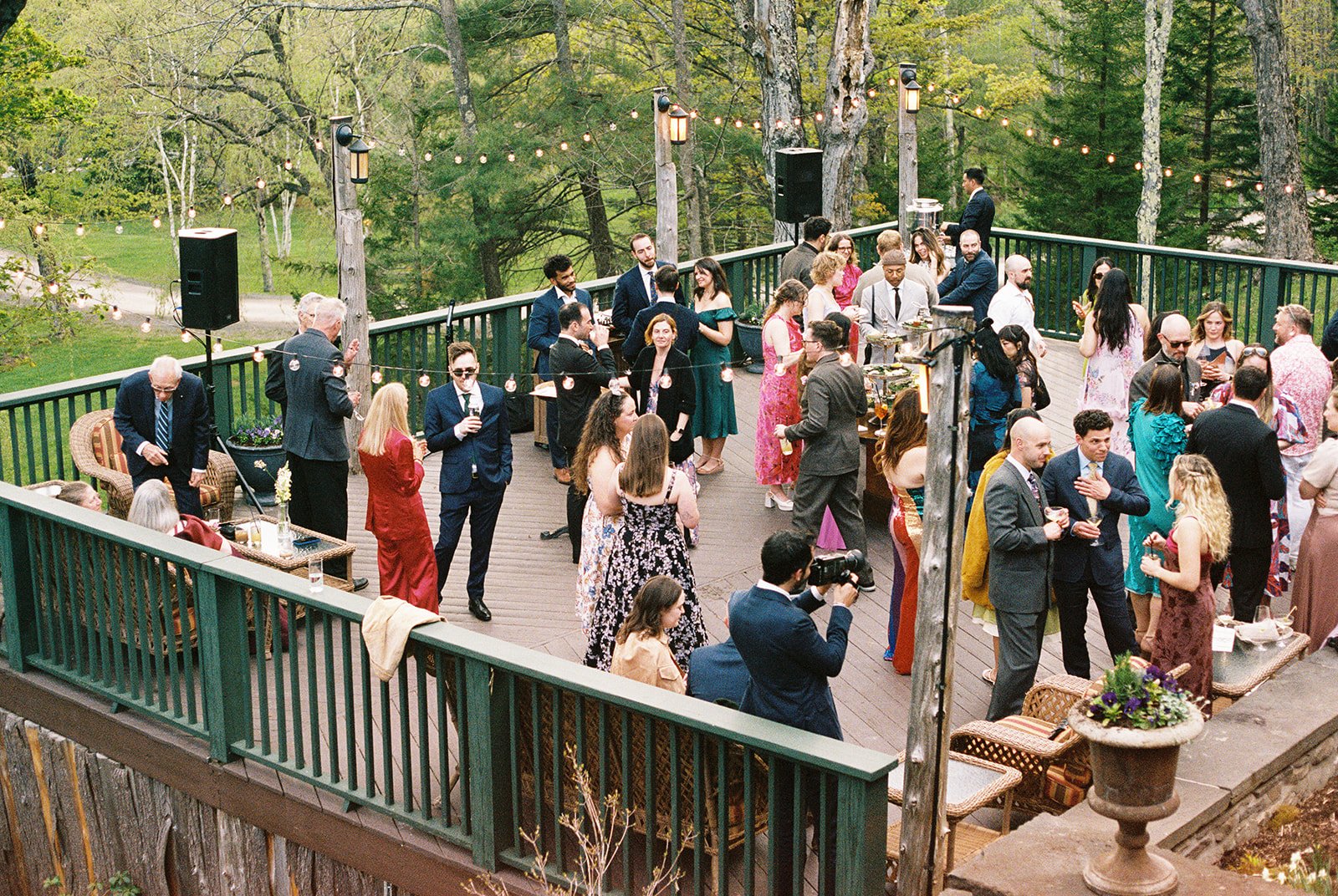 Film photo of wedding guests mingling beneath string lights on the terrace at Deer Mountain Inn.