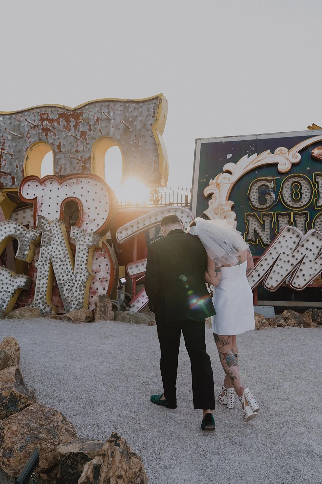 Bride and groom walking through the North Gallery at The Neon Museum during golden hour.