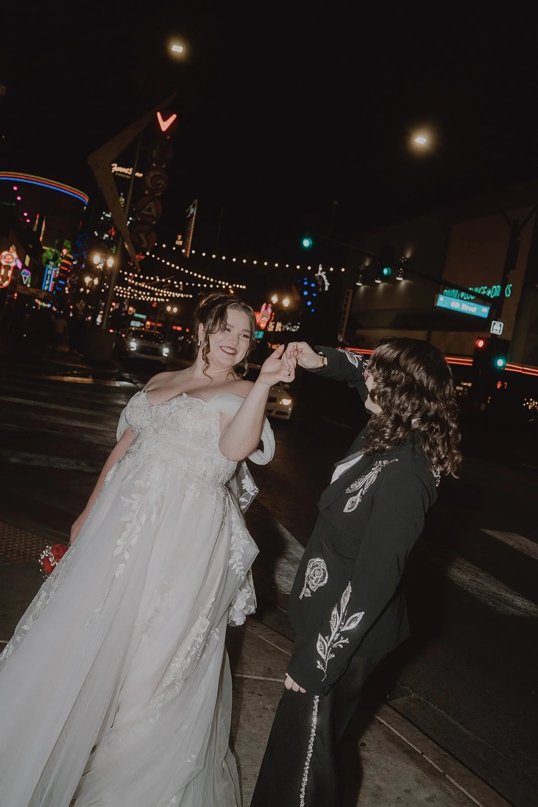 Couple twirling during nighttime Fremont Street wedding photos in Las Vegas.