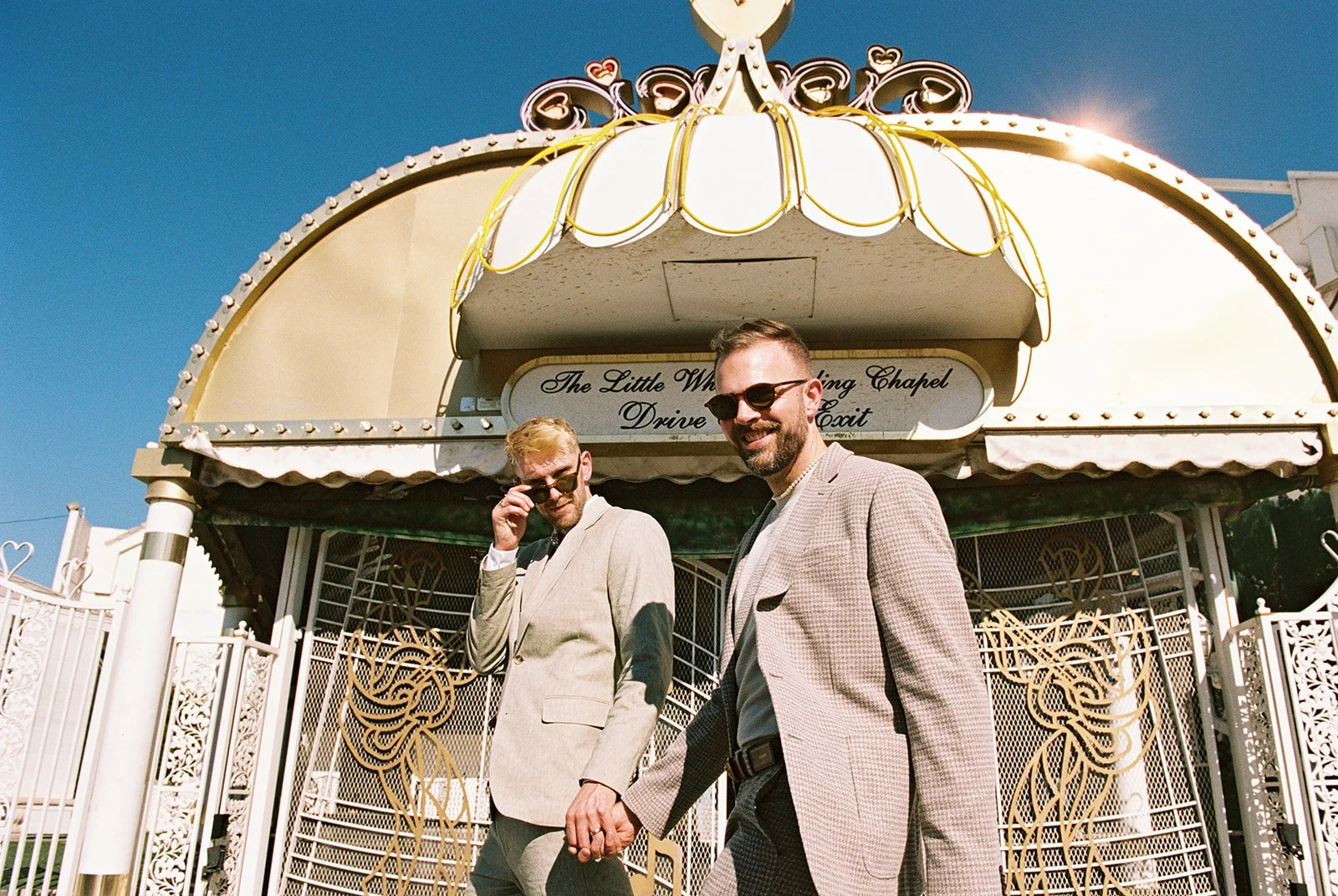 Couple wearing sunglasses and walking in front of the chapel on 35mm film.