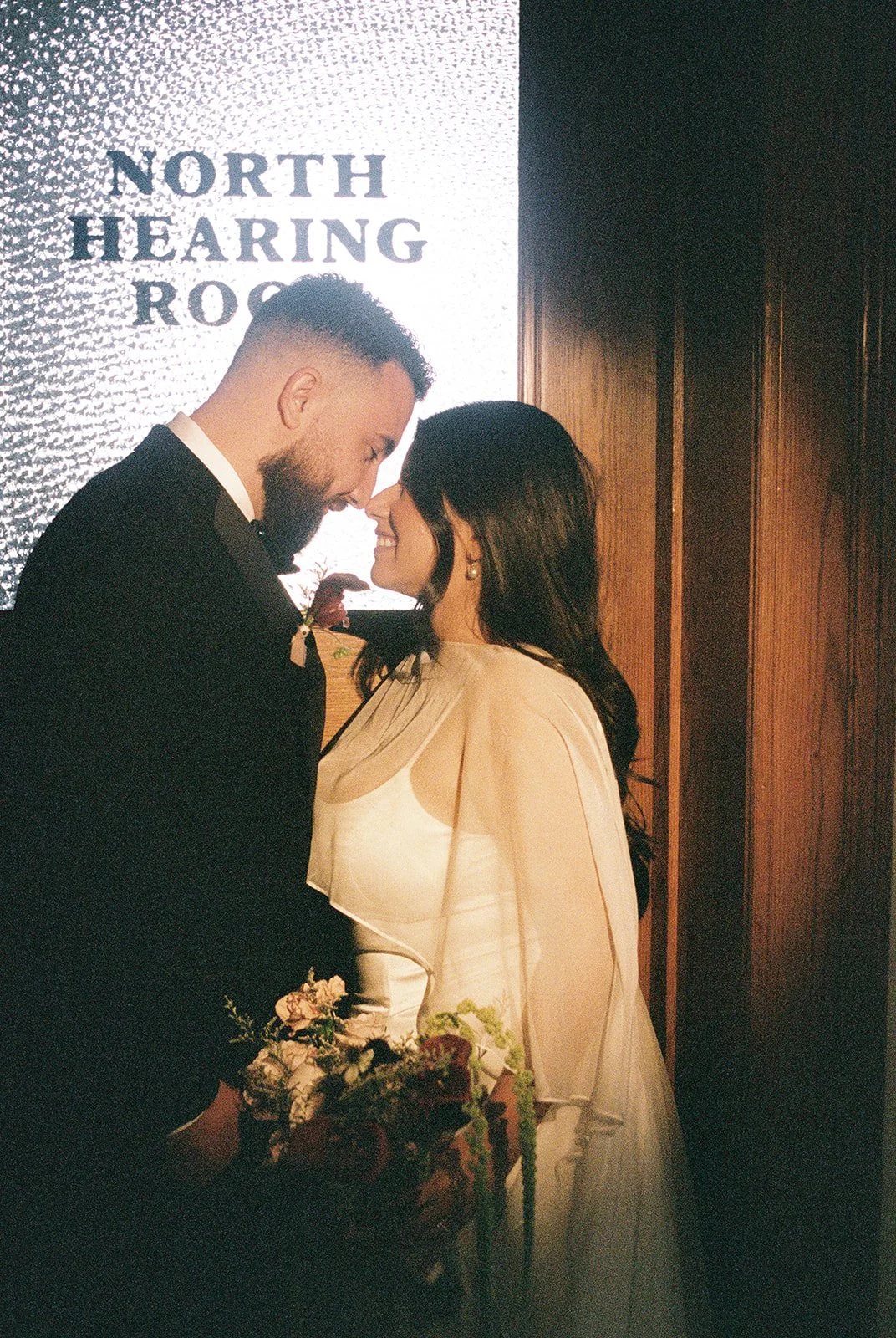 35mm film photo of a couple posing outside of the North Hearing Room at Old Orange County Courthouse.