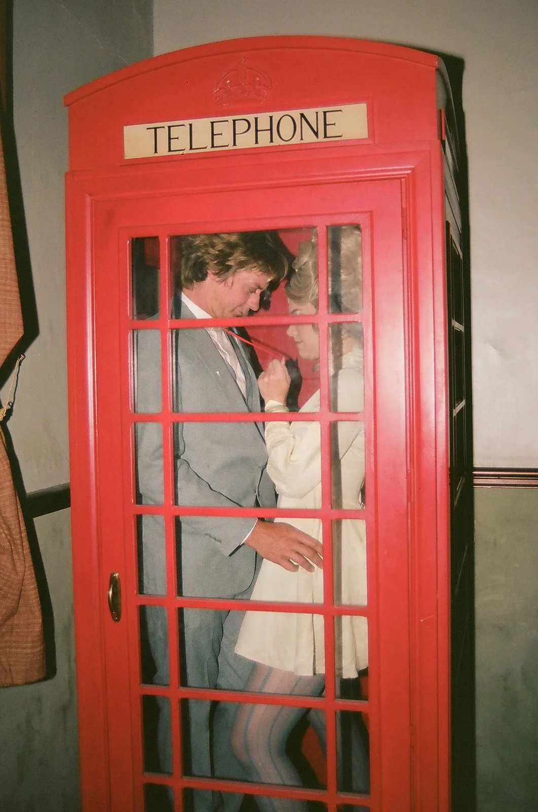 Couple posing inside a red vintage telephone booth for their Vintage Vegas wedding photos inside The Mint Tavern.