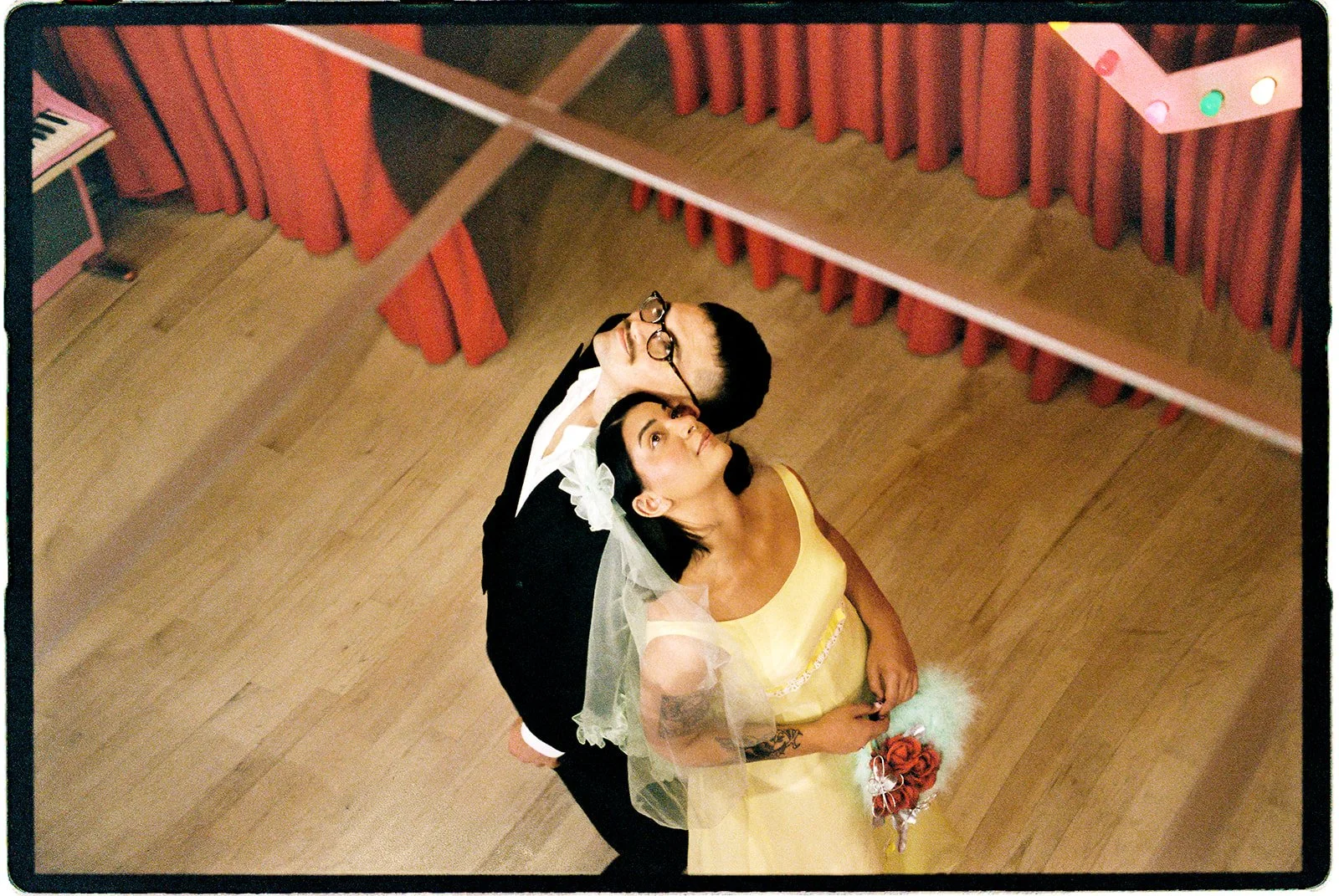 Overhead 35mm film portrait of a couple looking upward inside Sure Thing NYC, surrounded by vintage chapel details.