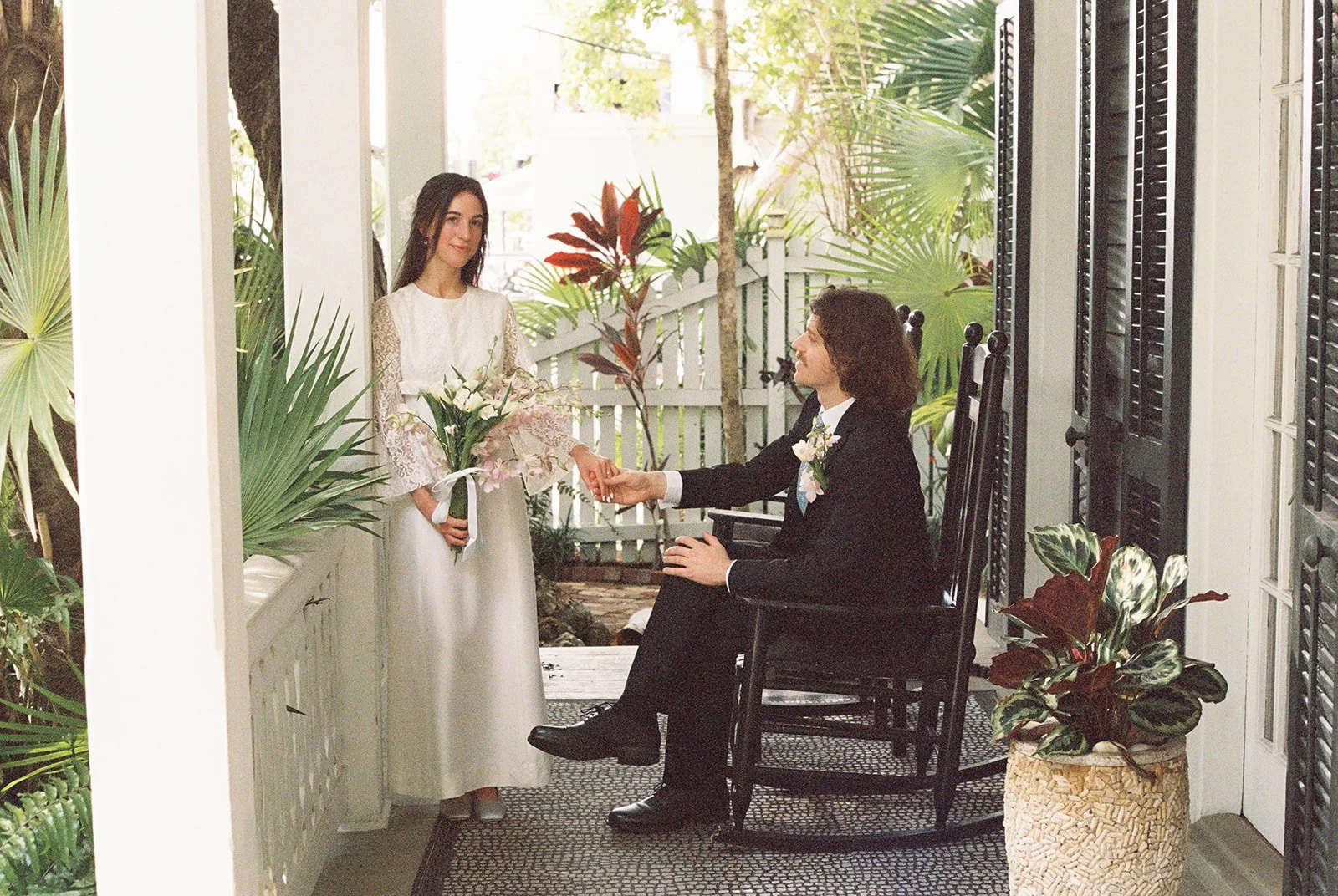 Bride and groom holding hands on the porch at Old Town Manor in Key West, Florida for their elopement.