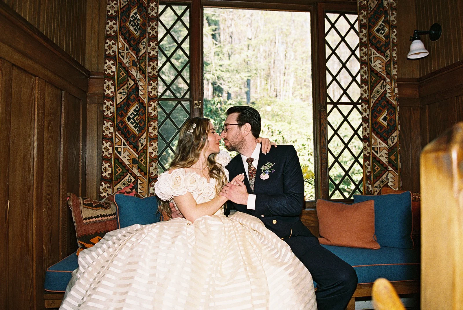 Film photo of a bride and groom sitting together on a sofa inside Deer Mountain Inn.
