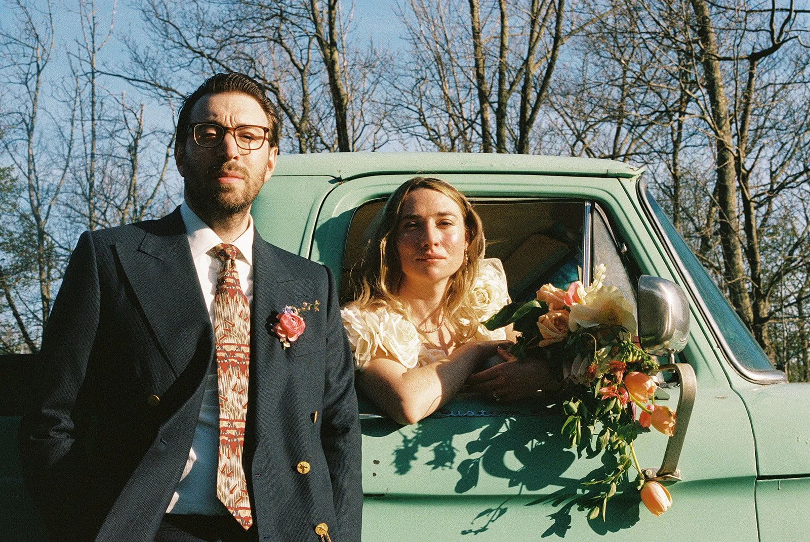 Bride and groom posing for portraits with a vintage green truck.