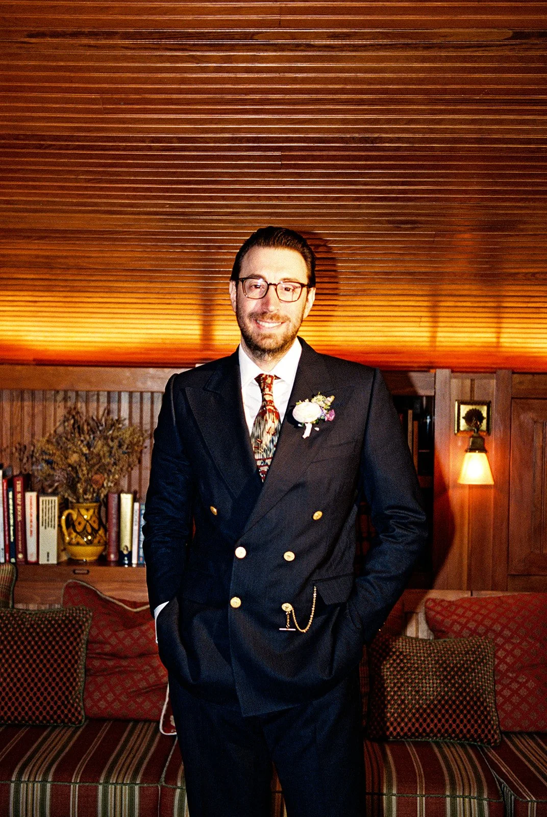 Film portrait of the groom wearing a double-breasted suit, patterned tie, boutonniere, and pocket watch inside the Attic at Deer Mountain Inn.