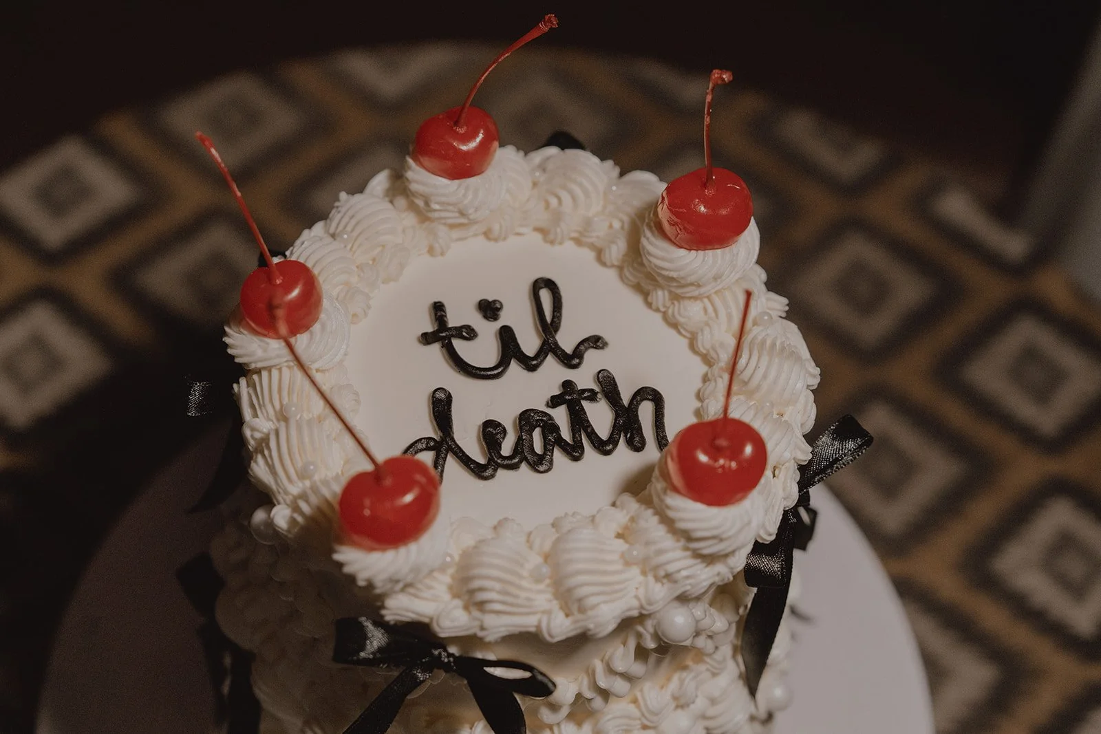 Close up shot of an elopement cake with til death written on the top.