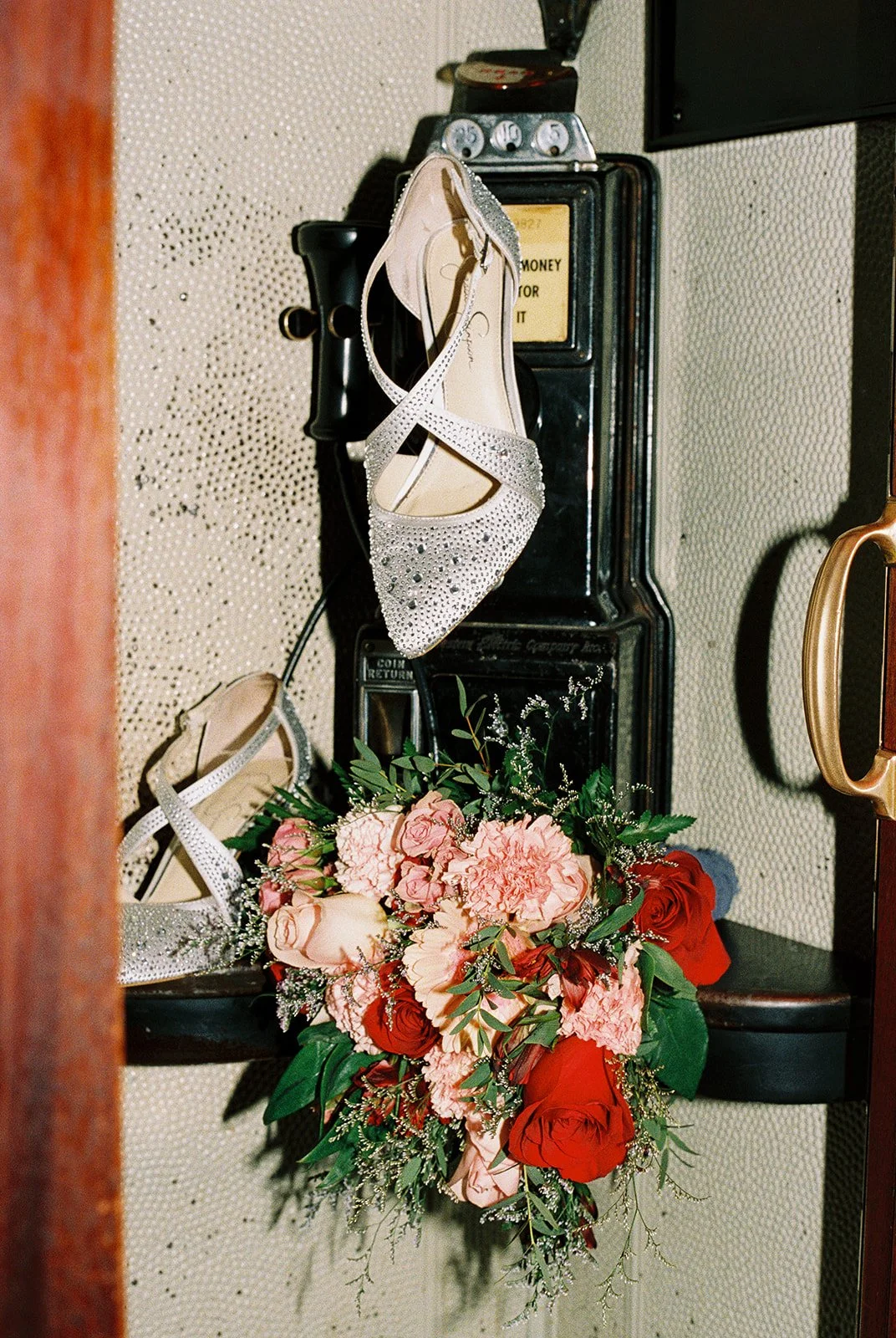 Film photo of the brides heels and bouquet styled inside the telephone booth at The Mob Museum.