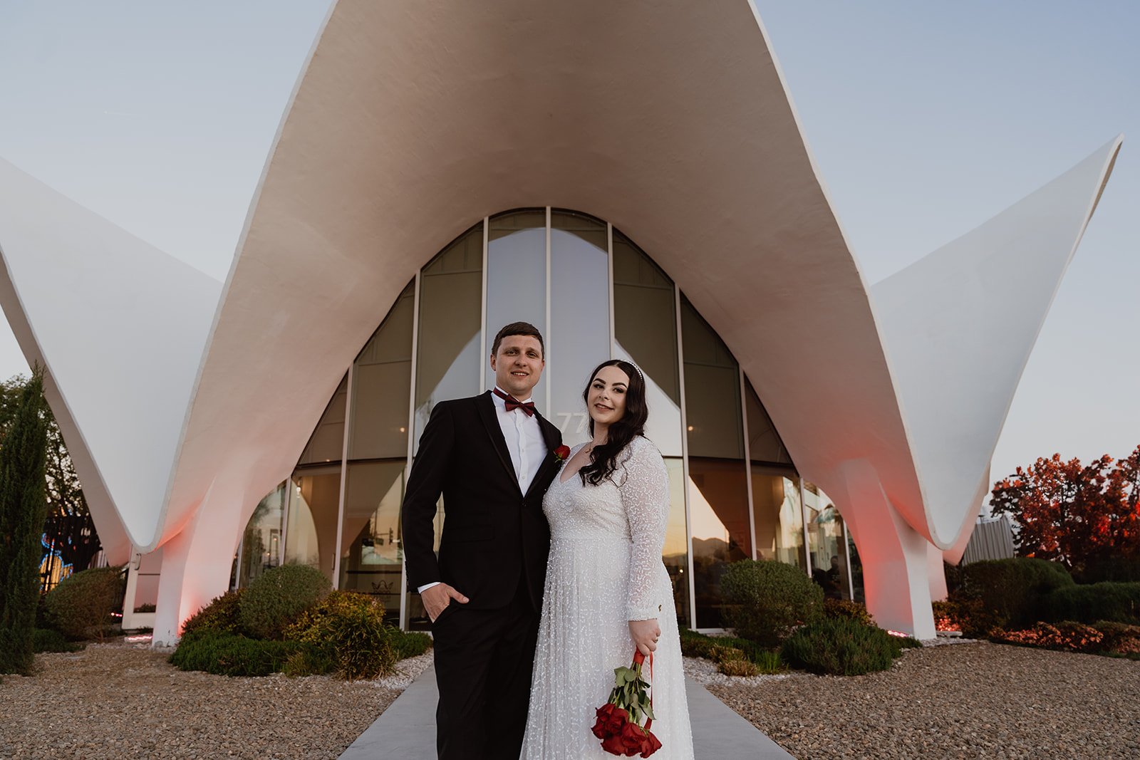 Bride and groom posing in front of the entrance of The Neon Museum in Las Vegas