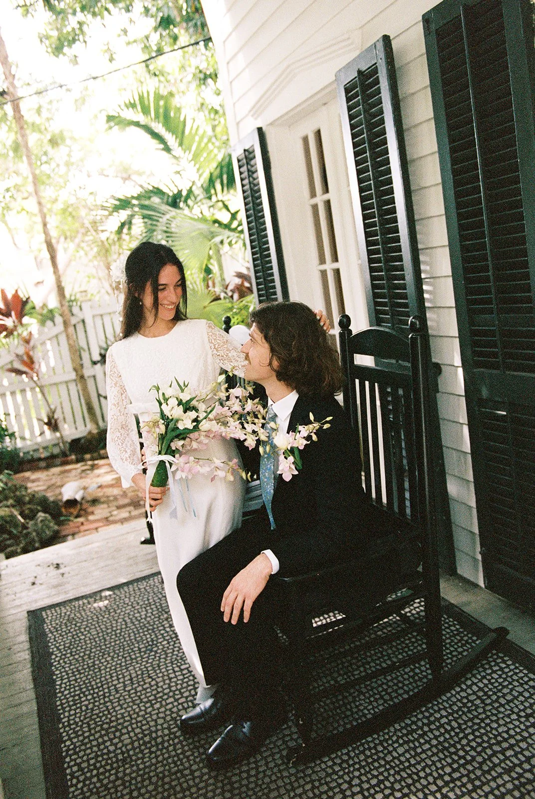 Bride and groom sharing a quiet moment on the porch rocking chairs at Old Town Manor in Key West.