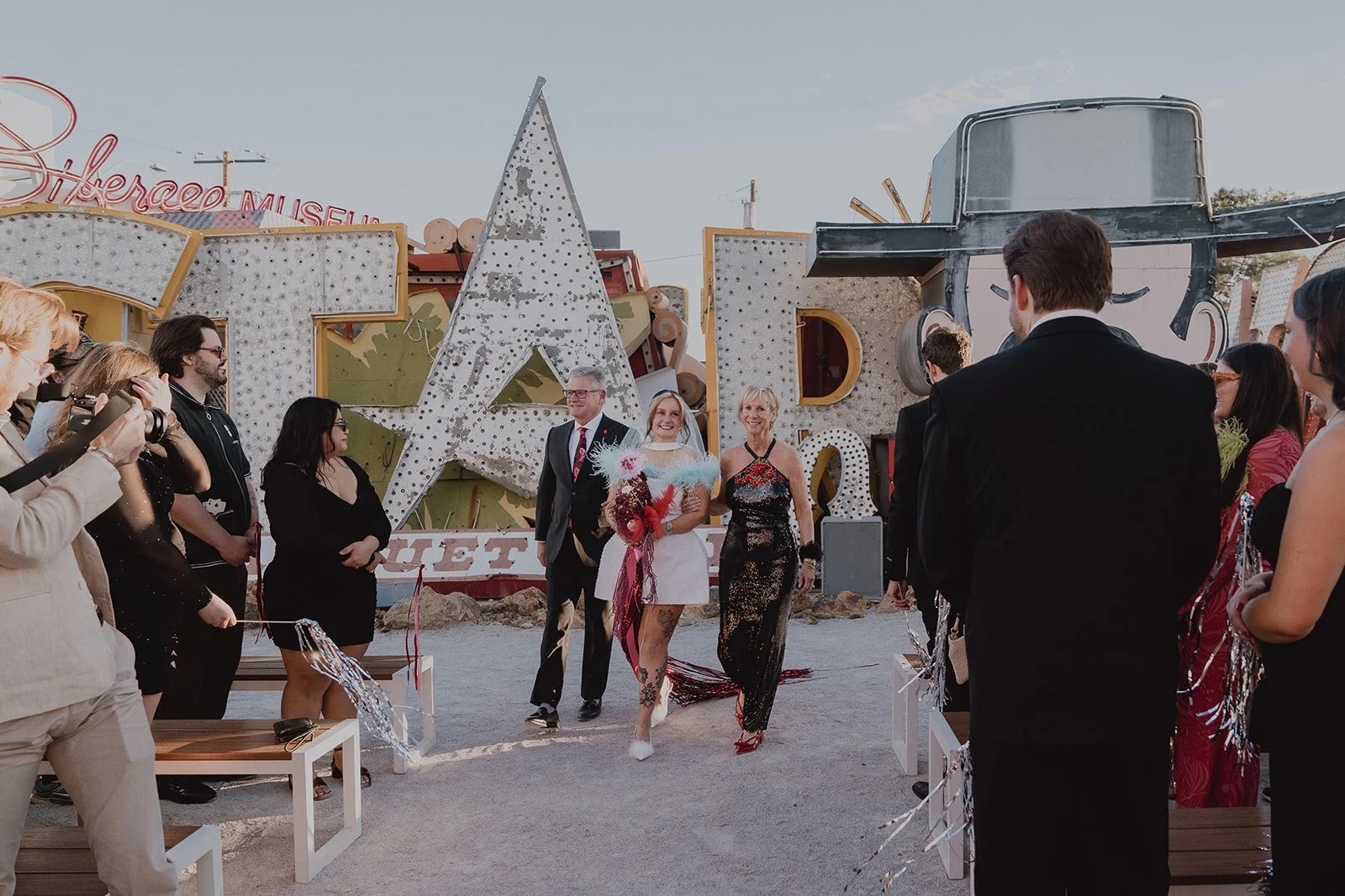 Bride being walked down the aisle by her parents for her Neon Museum Las Vegas wedding ceremony.