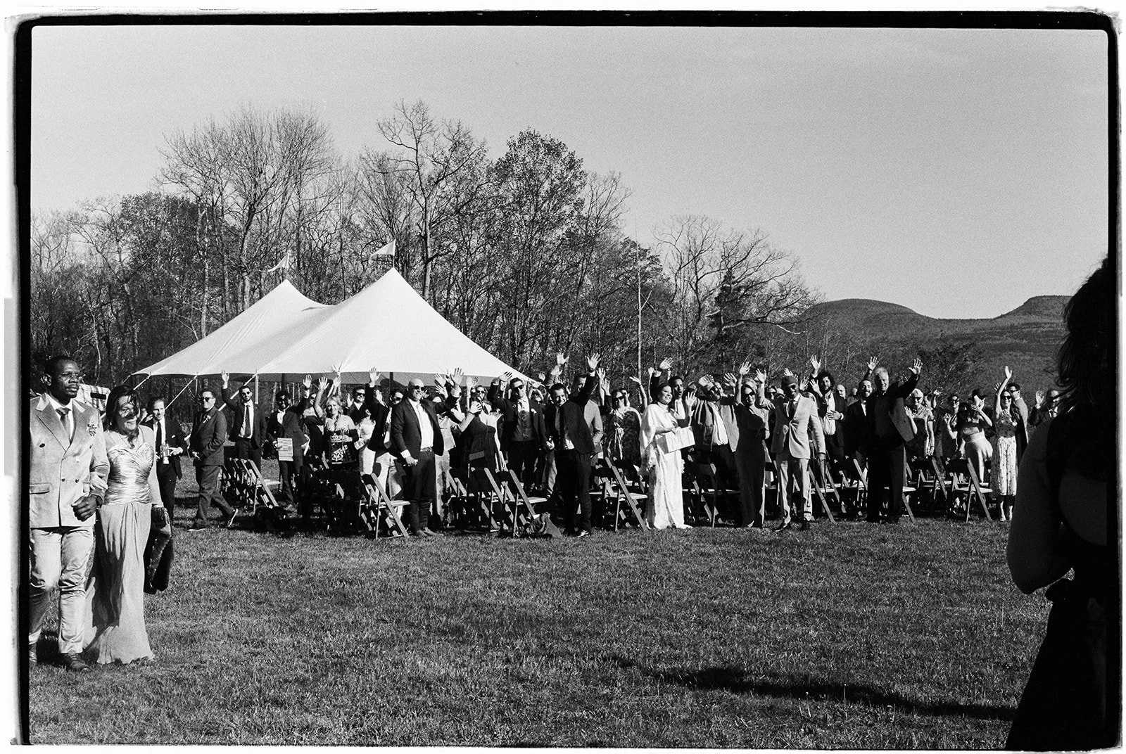 Black and white photo of guests cheering after a mountain ceremony on film.