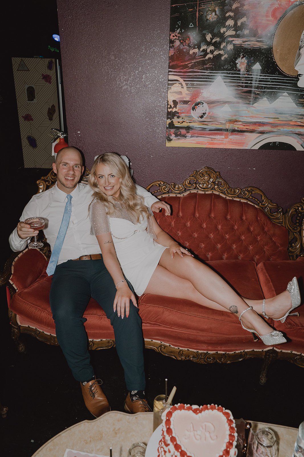 Bride and groom seated together on a velvet couch during their Velveteen Rabbit micro wedding reception.