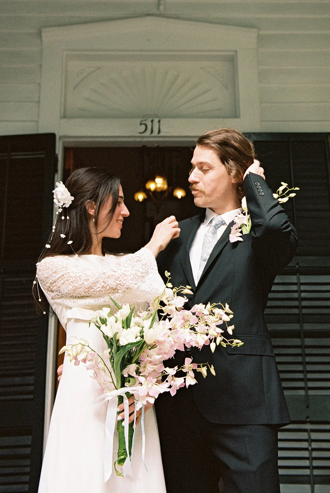 Bride adjusting groom’s boutonniere outside the original cypress doors at Old Town Manor in Key West.