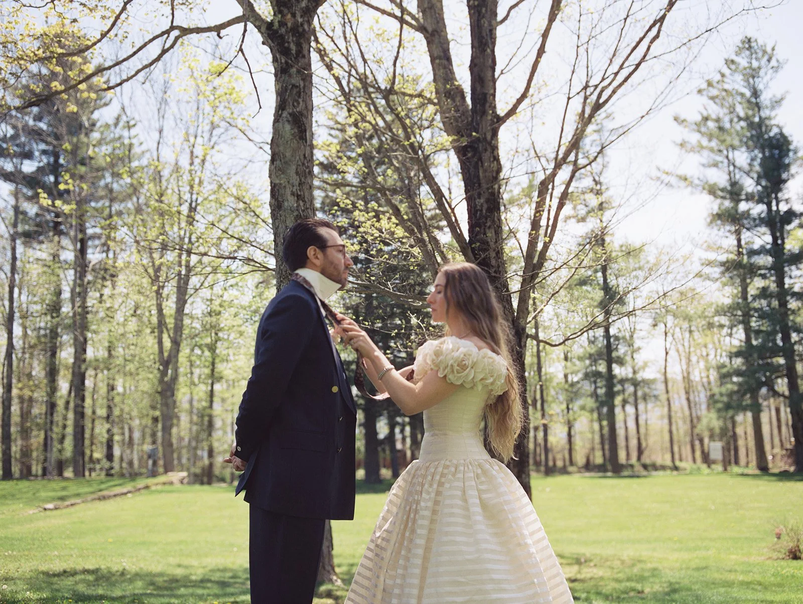 Bride adjusting the grooms tie during their first look outdoors.