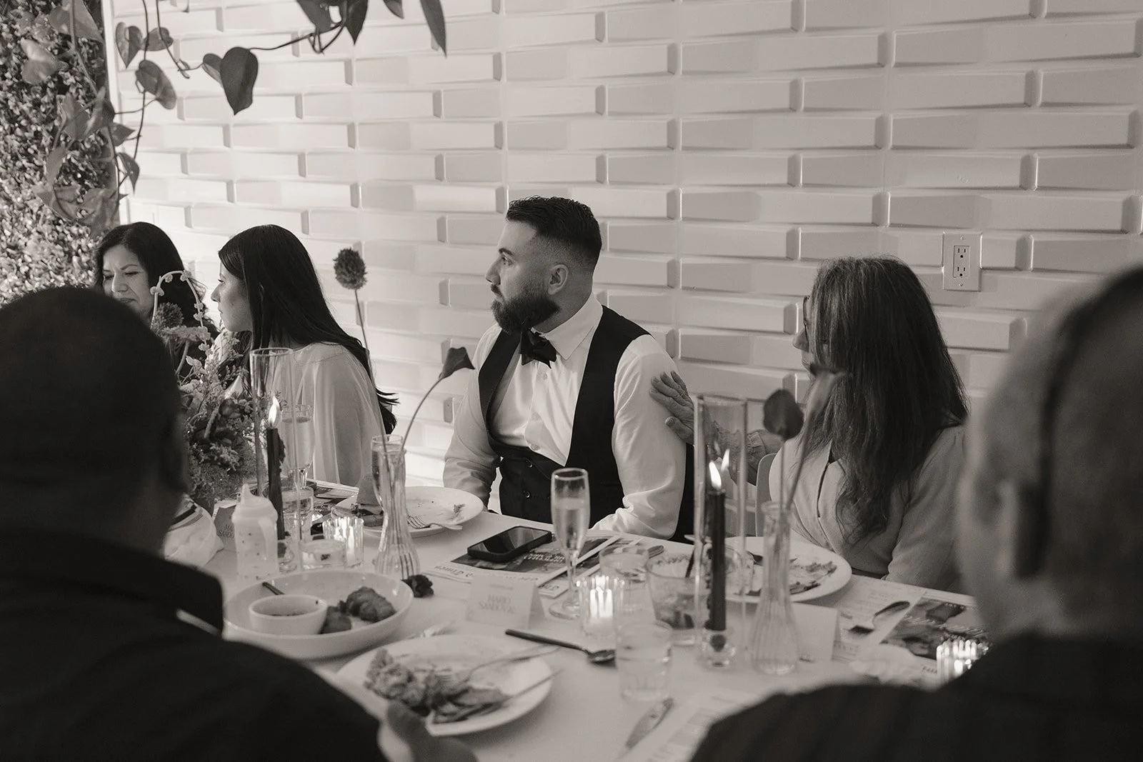 Black and white candid photo of a bride and groom mingling with guests during their micro wedding reception.