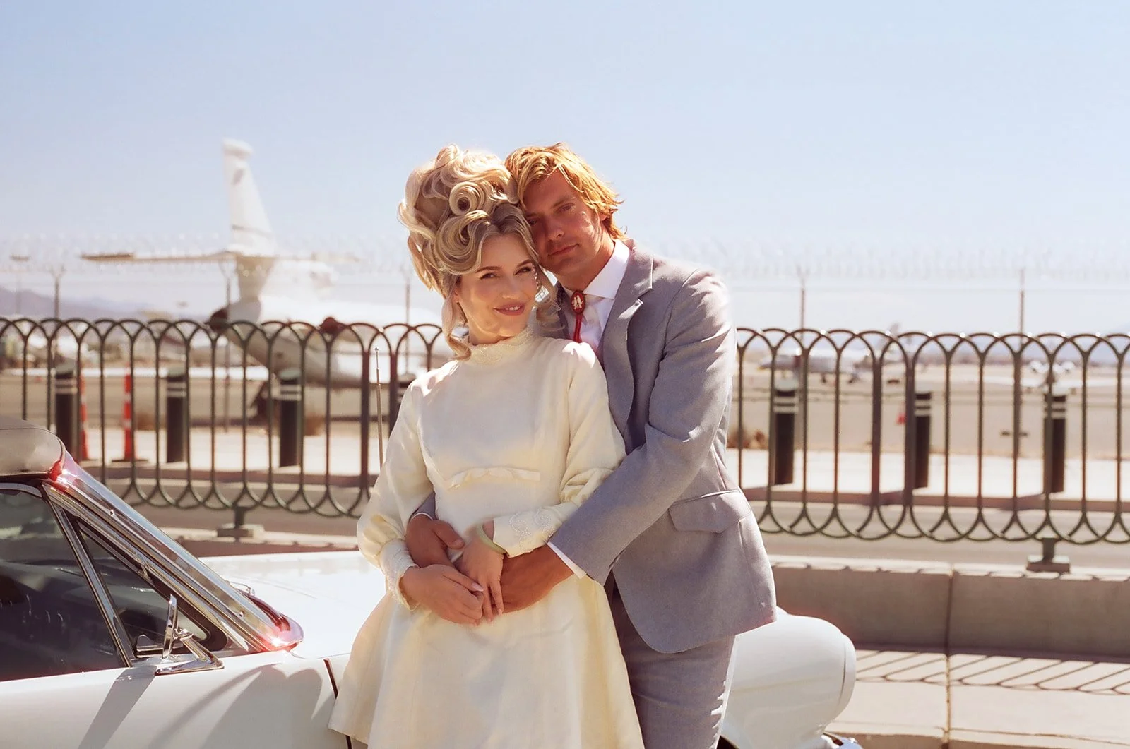 Couple posing for their vintage Vegas wedding photos in front of an airport.