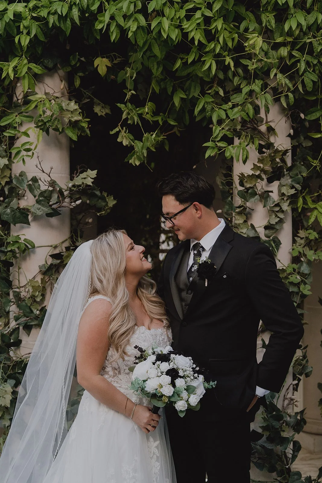 Bride and groom smiling at each other in front of lush greenery at the Venus Garden inside Caesars Palace.