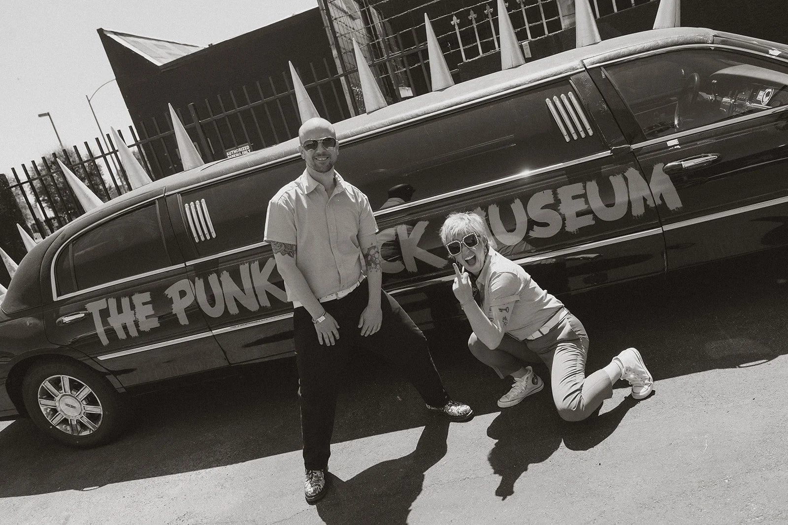Couple posing in front of a limo that says Punk Rock Museum.