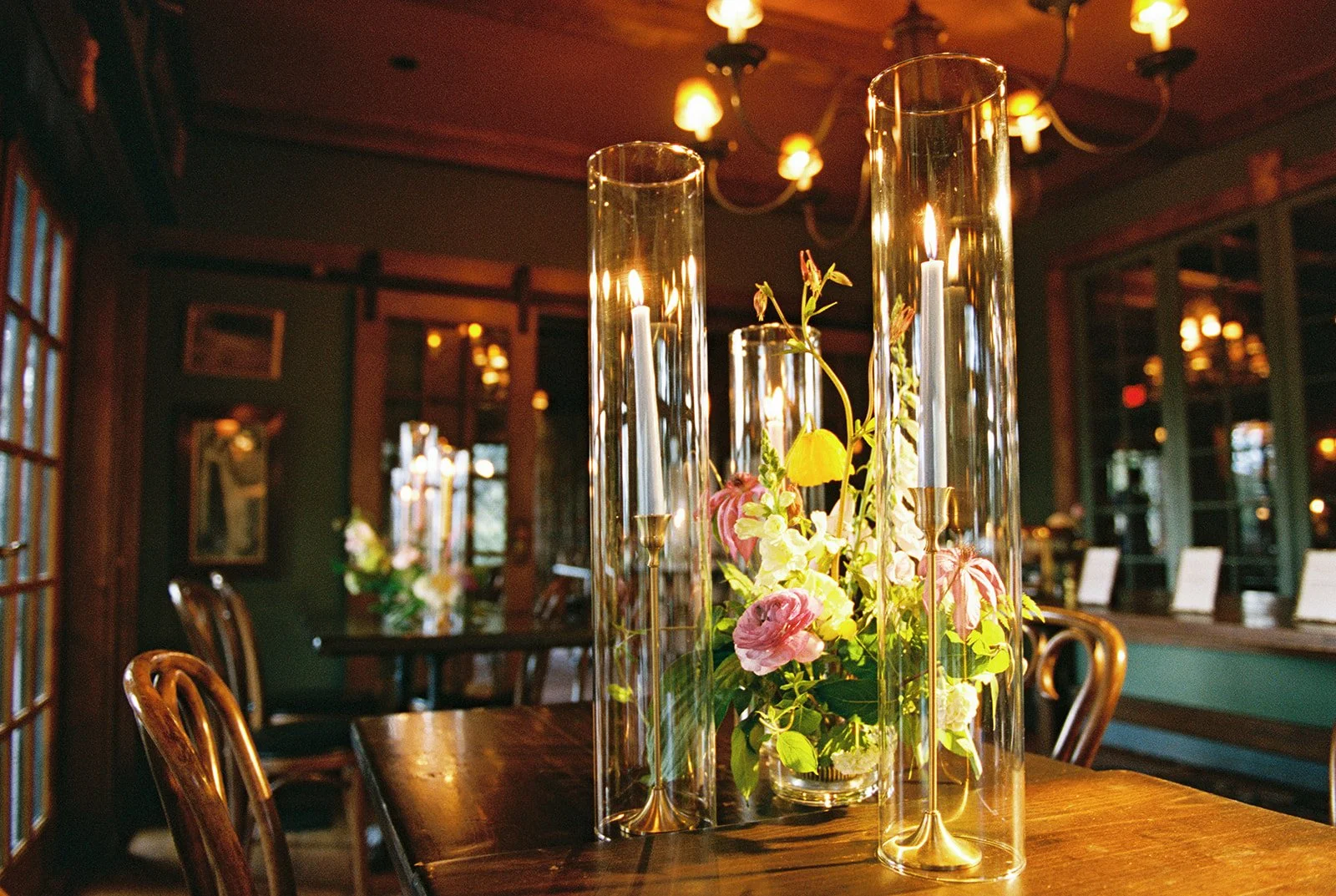 Film photo of colorful flowers and taper candles arranged on a reception table inside Deer Mountain Inn.