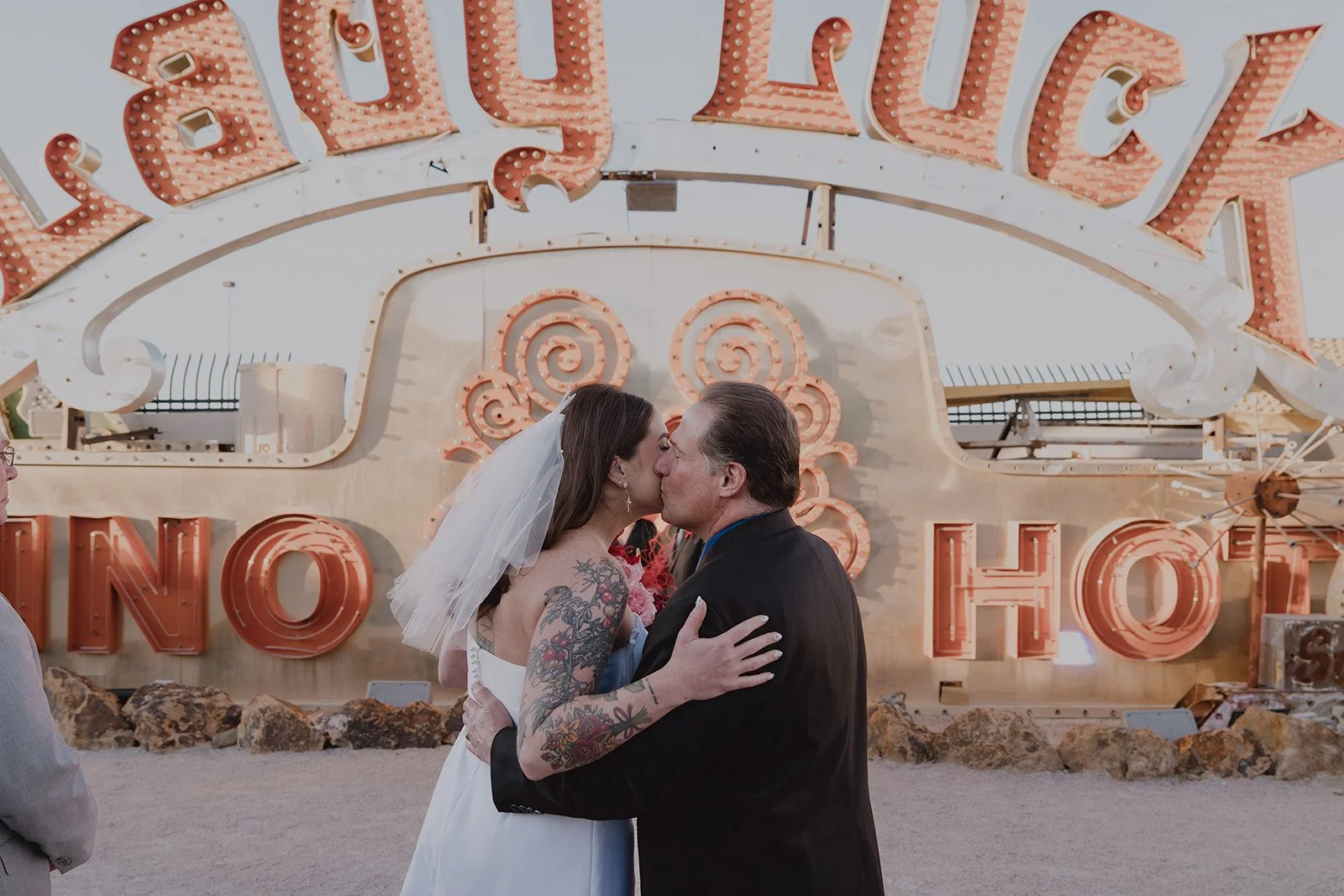 Bride and her father sharing a kiss in front of the Lady Luck sign during their Neon Museum Las Vegas wedding.