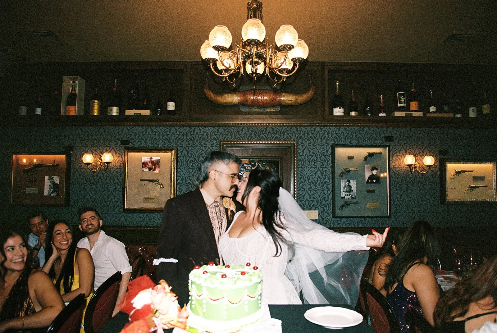 Bride and groom kissing in front of their wedding cake during their  Las Vegas wedding reception at Golden Steer.