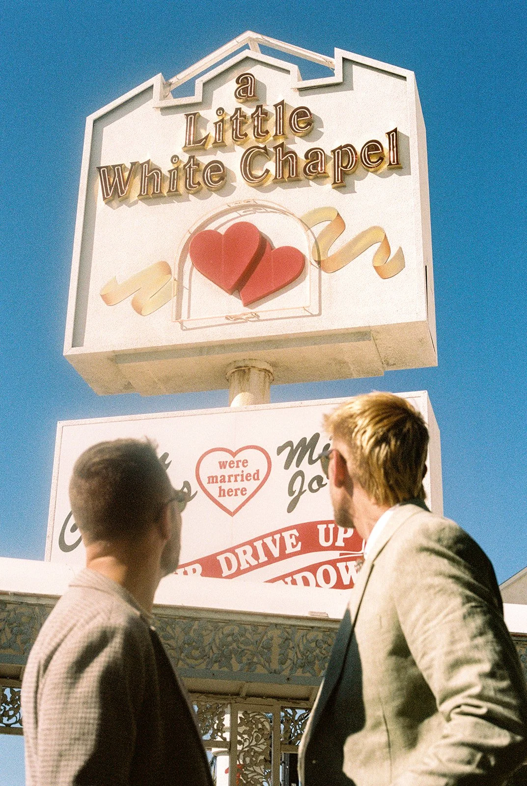 35mm film photo of a couple looking up at the a Little White Chapel sign on 35mm film.