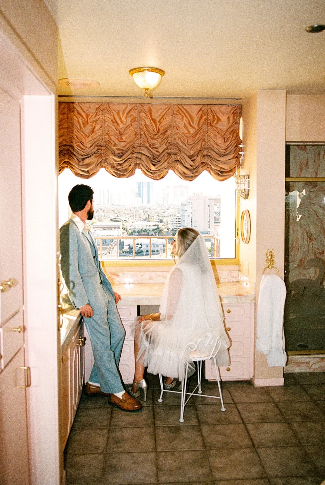 Couple sitting at a vintage vanity inside the Jackie Gaughan Suite at El Cortez