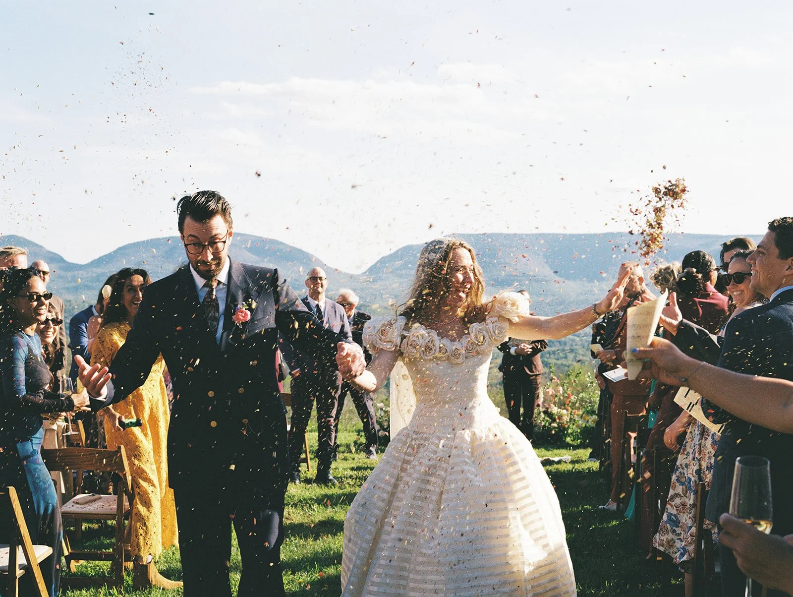 Bride and groom exiting their wedding ceremony during a petal toss on film.