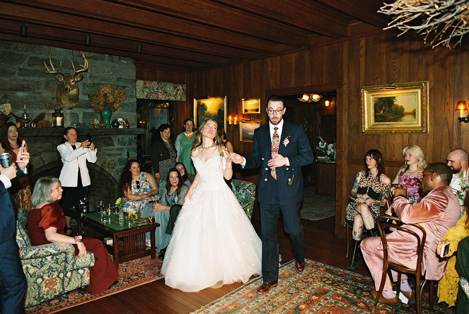 Candid film photo of the bride and groom entering their Deer Mountain Inn wedding reception as guests watch.