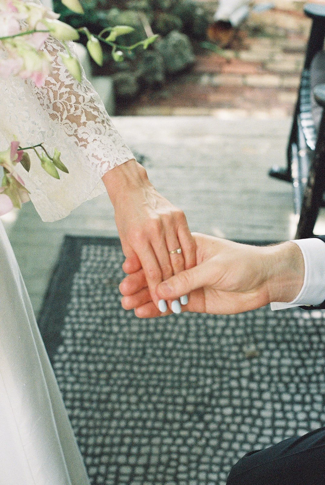 Close up shot of a bride and groom holding hands.