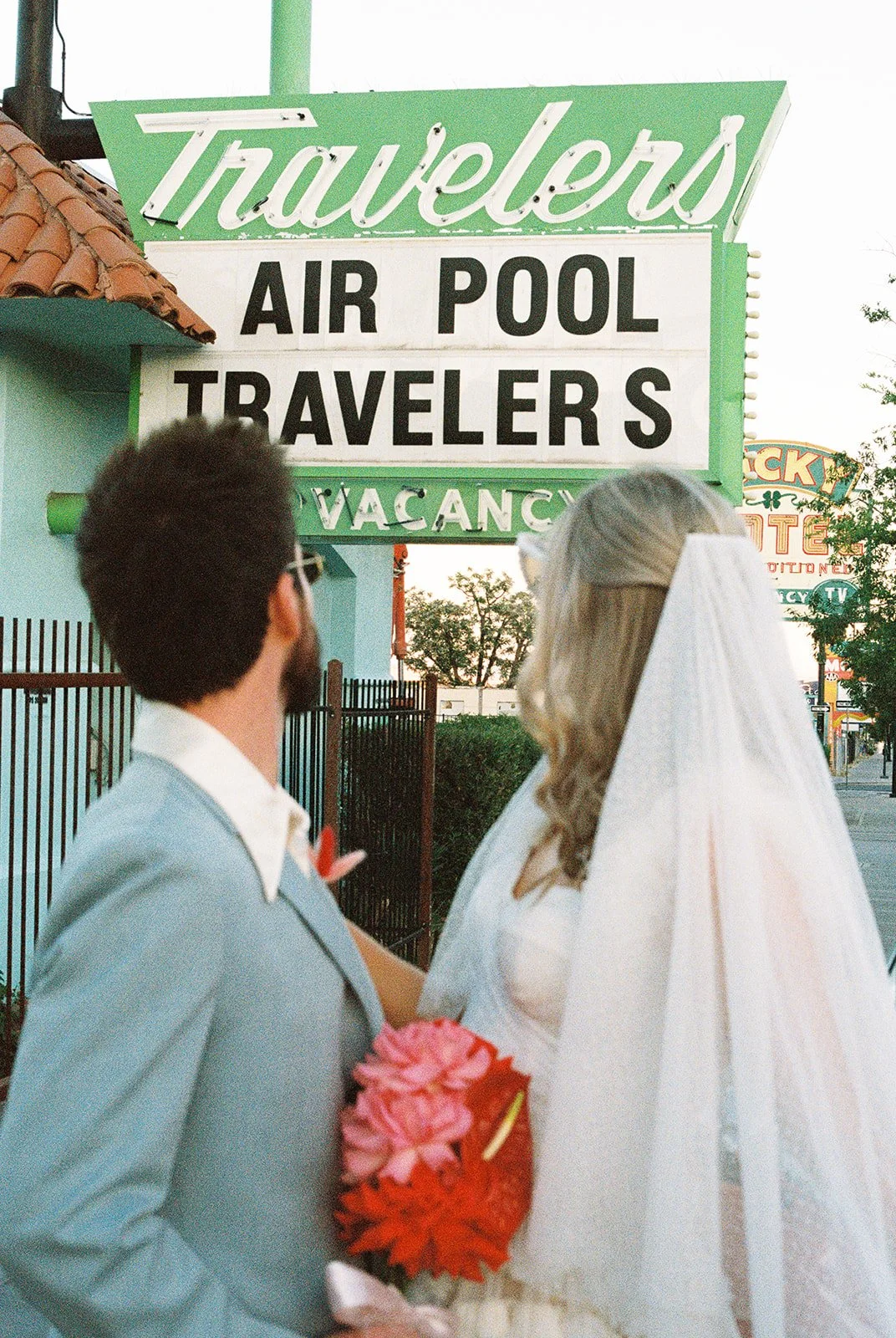 Bride and groom looking up at the Travelers Motel sign in Las Vegas on 35mm film.